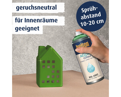 Hand hält eine Helton Aqua Colours Sprühdose in Laubgrün RAL 6002 zum Lackieren eines Hausmodells. Produkt ist geruchsneutral für Innenräume.