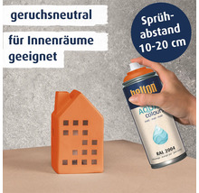Eine Hand sprüht mit der Helton Aqua Colours Sprühdose auf ein kleines Hausobjekt mit dem Hinweis auf Geruchsneutralität und Sprühabstand.