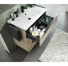 Waschtischunterschrank in Holzoptik mit weißem Waschbecken und ausgezogener Schublade inklusive Ordnungssystem und Handtuchhalter im Badezimmer.