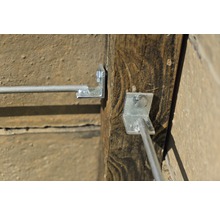 Detailansicht von einem Holzpfosten mit einem daran befestigten Drahtseilhalter.