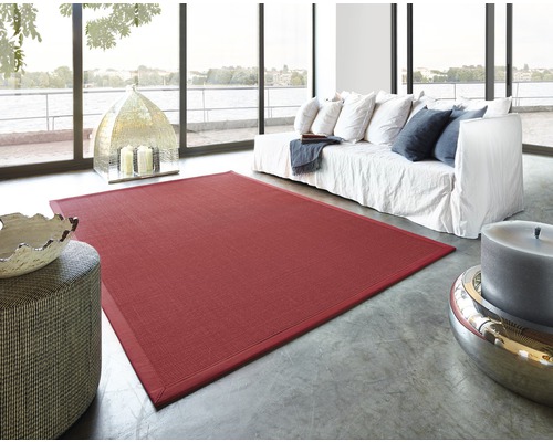 Wohnzimmer mit rotem Teppich, Sofa und dekorativen Elementen vor Panoramafenster