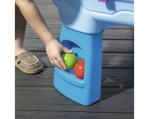 Detailansicht eines Spieltisches mit Aufbewahrungsfach und bunten Bällen.