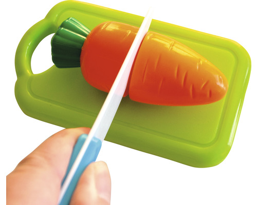 Spielzeug Karotte wird auf einem Schneidebrett mit einem Messer geschnitten