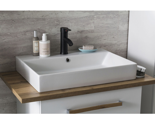 Waschbecken im Badezimmer mit Armatur, Seife und Kosmetikprodukten