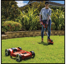 Frau arbeitet im Garten mit Rasentrimmer und Mähroboter.