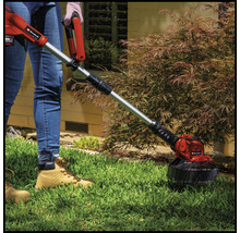 Person benutzt einen Rasentrimmer der Marke Einhell im Garten.