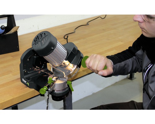 Person schärft Kettensäge mit Kettenschärfgerät