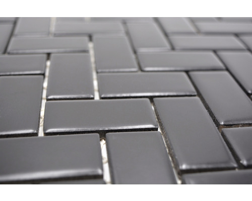 Nahaufnahme eines Mosaiks aus rechteckigen Fliesen, die im Fischgrätmuster angeordnet sind.