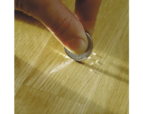 Eine Person entfernt mit einer Münze Kratzer von einer Holzoberfläche.