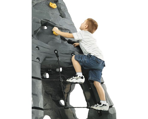 Kind klettert an einer grauen Kletterwand mit gelben Griffen und einem schwarzen Seilnetz.