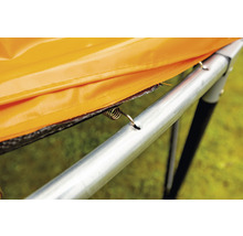 Detailansicht einer Trampolinfeder, die eine orangefarbene Randabdeckung am Trampolinrahmen befestigt.