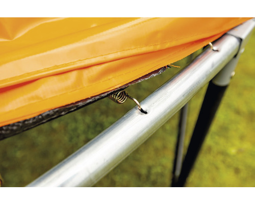 Detailansicht einer Trampolinfeder, die eine orangefarbene Randabdeckung am Trampolinrahmen befestigt.
