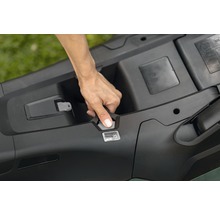 Hand öffnet das Batteriefach eines Rasenmähers