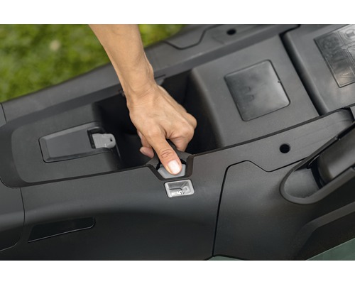 Hand öffnet das Batteriefach eines Rasenmähers