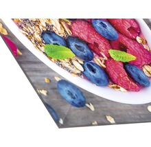 Nahaufnahme einer Schale mit Müsli, Himbeeren, Heidelbeeren und Minze auf einem Holztisch