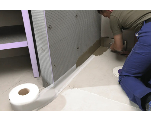 Badezimmerszene mit Dichtband, Dämmplatten und Handwerker bei der Arbeit