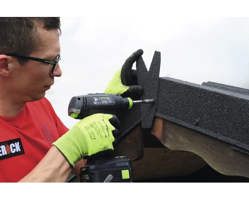 Mann befestigt Dachschindeln mit einem Akkuschrauber