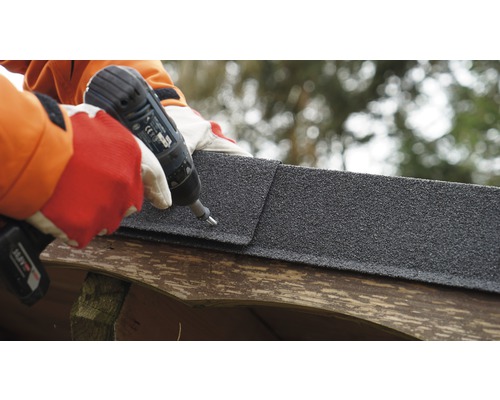 Person befestigt Bitumenschindel mit Akku-Bohrschrauber