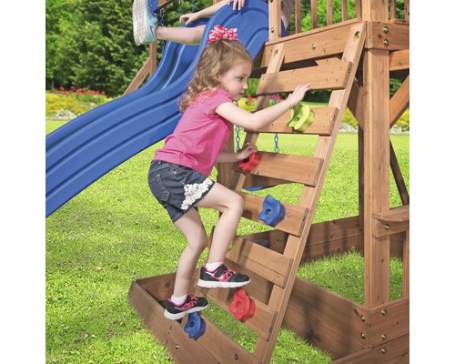 Mädchen klettert auf einer Holzleiter mit farbigen Klettergriffen in einem Spielturm