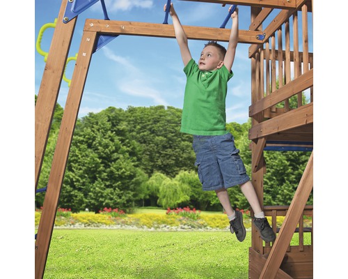 Ein Kind hangelt sich auf einem Spielplatz an einer Sprossenwand aus Holz entlang.