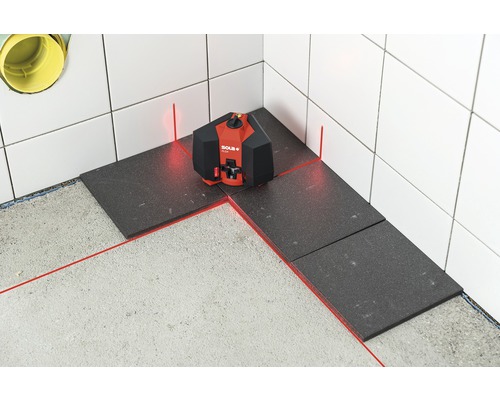 Roter Linienlaser beim Verlegen dunkler Fliesen im Badezimmer