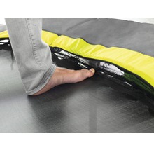 Detailaufnahme eines Trampolins mit Fuß auf der Sprungfläche