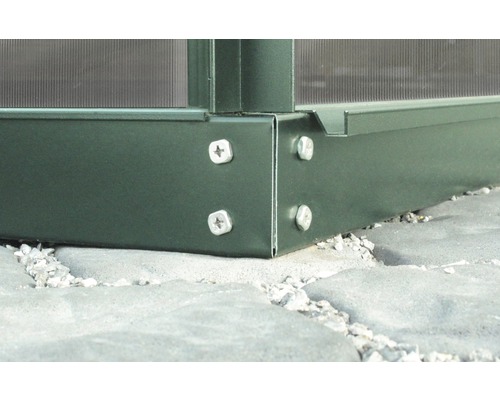 Detailaufnahme eines Gewächshausrahmens aus Metall mit Schraubenbefestigung auf Steinboden