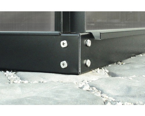 Detailaufnahme einer Gewächshaus Ecke mit Schrauben auf Steinboden.