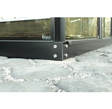 Detailaufnahme eines Gewächshausrahmens aus Metall mit Schrauben auf Steinpflaster. Vitavia Logo.
