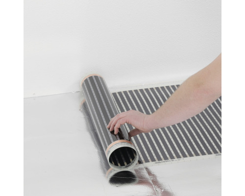 Flächenheizung ausgerollt auf einer reflektierenden Oberfläche, mit Hand