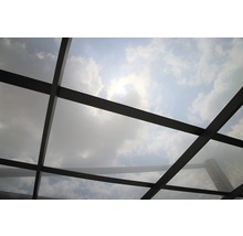 Ansicht einer Glasdachkonstruktion mit Himmel und Wolken im Hintergrund.
