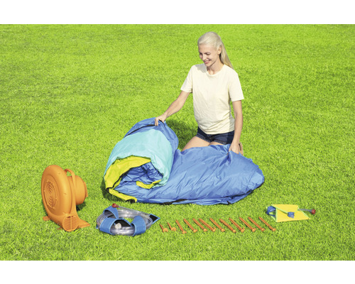 Aufblasbare Hüpfburg mit Gebläse und Zubehör auf einer Wiese.