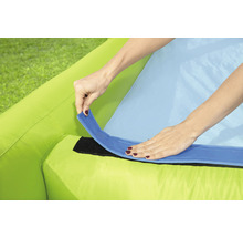 Detailaufnahme eines aufblasbaren Produkts mit einer Person, die eine blaue Lasche an einem grünen Stoff befestigt.