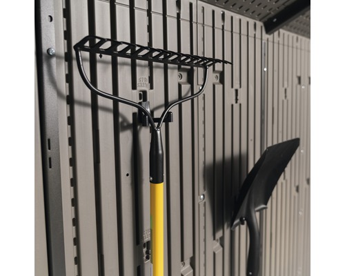 Gartenrechen mit gelbem Griff und Schaufel, an einer Lagerwand befestigt