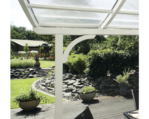 Detailansicht einer Terrassenüberdachung mit weißem Rahmen und durchsichtigem Dach in einem Garten.