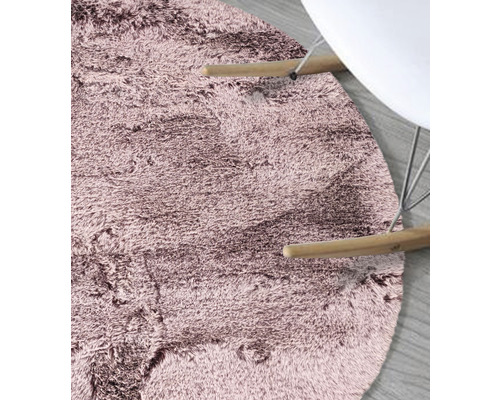 Detailansicht eines runden, kurzflorigen Teppichs neben einem Stuhl