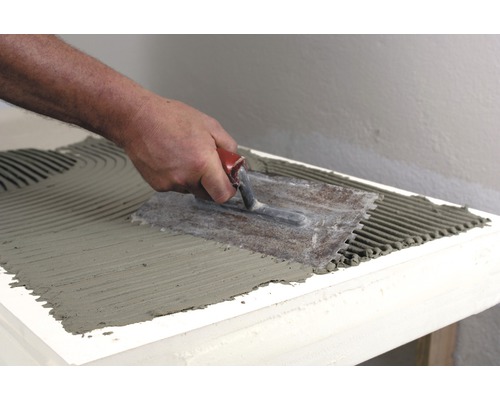 Auftragen von Fliesenkleber mit einer Glättkelle