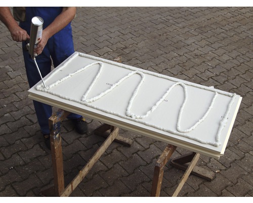 Handwerker trägt Bauschaum auf Dämmplatte auf