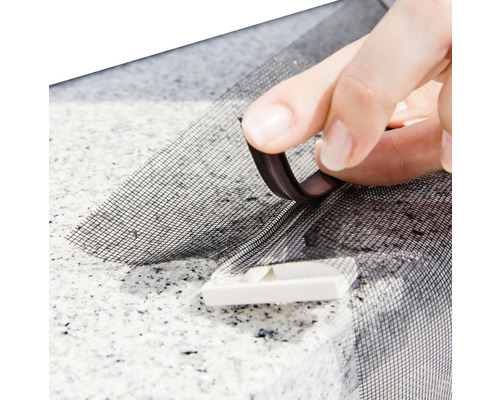 Nahaufnahme einer Hand, die ein Fliegengitter mit Magnetband anbringt