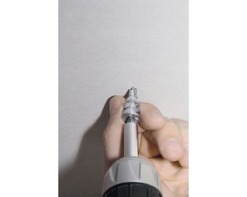 Ein Mann schraubt einen Dübel mit einem Akkuschrauber in die Wand.