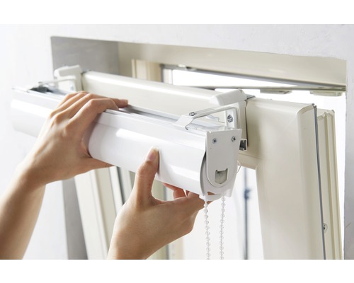 Person montiert Rollo am Fensterrahmen