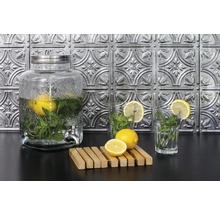 Wasserspender mit Zitronen und Minze, zwei Gläser mit Zitronenscheiben und eine Holzunterlage