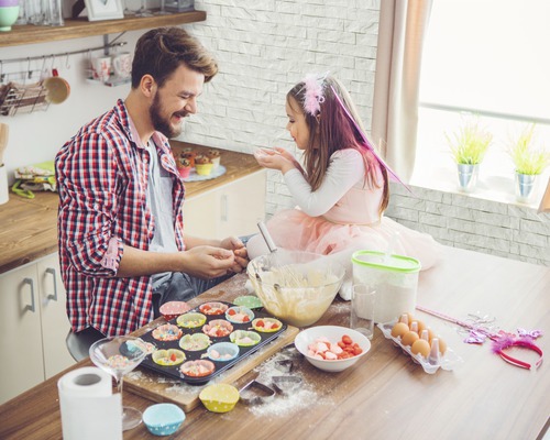 Vater und Tochter backen gemeinsam Muffins in der Küche.
