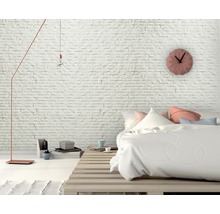 Schlafzimmer mit Bett auf Holzpalette, Wanduhr und Stehlampe