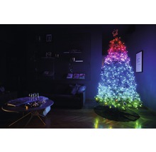 Weihnachtsbaum mit Lichtern im Wohnzimmer, daneben ein Tisch mit Dekoration