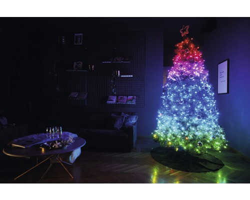 Weihnachtsbaum mit Lichtern im Wohnzimmer, daneben ein Tisch mit Dekoration
