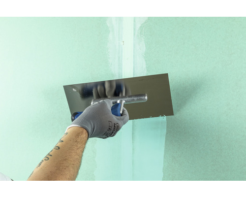 Eine Person glättet eine Wand mit einer Glättkelle.