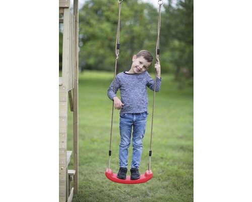 Junge steht auf einer Kinderschaukel mit Seilen im Garten.