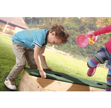Kinder spielen mit einem Sandkasten im Garten.