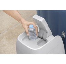Eine Person legt eine Wasserflasche in einen Mülleimer.